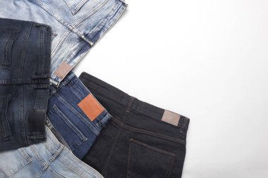 Beyaz arka planda deri etiketleri olan bir sürü değişik moda kot pantolon.