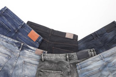 Beyaz arka planda deri etiketleri olan bir sürü değişik moda kot pantolon.