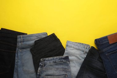 Sarı arka planda farklı kot pantolonlar. Üst Manzara. Boşluğu kopyala