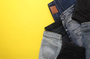 Sarı arka planda farklı kot pantolonlar. Üst Manzara. Boşluğu kopyala