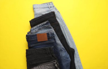 Sarı arka planda farklı kot pantolonlar. Üst görünüm.