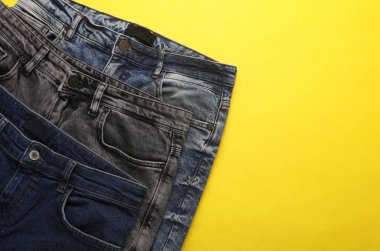 Sarı arka planda farklı kot pantolonlar. Üst Manzara. Boşluğu kopyala