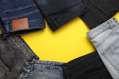 Sarı arka planda farklı kot pantolonlar. Üst Manzara. Boşluğu kopyala