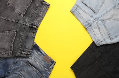 Sarı arka planda farklı kot pantolonlar. Üst Manzara. Boşluğu kopyala