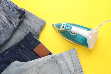 Demir, sarı arka planda bir sürü kot ütüler. Üst görünüm