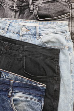 Sarı arka planda farklı kot pantolonlar.