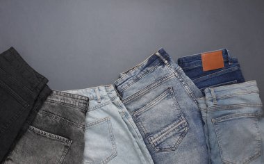 Gri arka planda bir sürü kot pantolon. Üst Manzara. Boşluğu kopyala