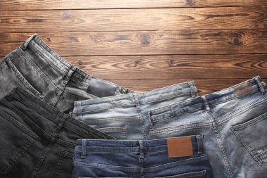 Ahşap arka planda bir sürü kot pantolon. Üst görünüm.
