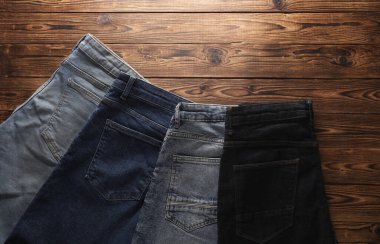 Ahşap arka planda bir sürü kot pantolon. Üst görünüm.