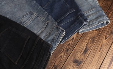 Ahşap arka planda bir sürü kot pantolon. Üst görünüm.