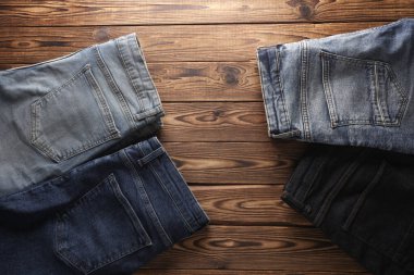 Ahşap arka planda bir sürü kot pantolon. Üst görünüm.