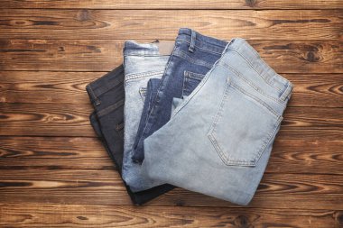 Ahşap arka planda bir sürü kot pantolon. Üst görünüm.