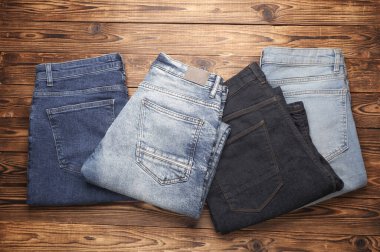 Ahşap arka planda bir sürü kot pantolon. Üst görünüm.