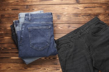 Ahşap arka planda bir sürü kot pantolon. Üst görünüm.