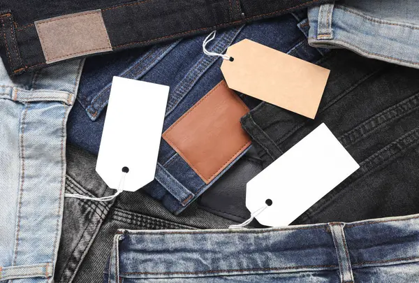 İçinde boş kağıt etiketler olan bir sürü değişik moda kot pantolonlar. Alışveriş, satış konsepti.