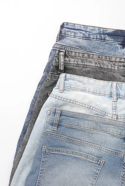 Beyaz arka planda farklı kot pantolonlar.