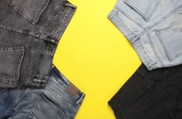 Sarı arka planda farklı kot pantolonlar. Üst Manzara. Boşluğu kopyala