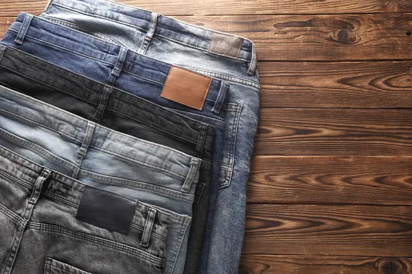Ahşap arka planda bir sürü kot pantolon. Üst görünüm.