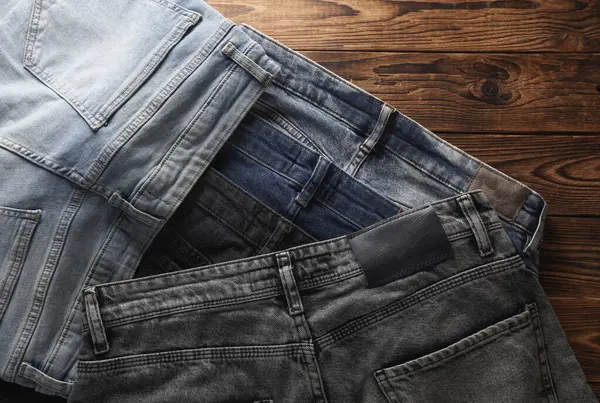 Ahşap arka planda bir sürü kot pantolon. Üst görünüm.