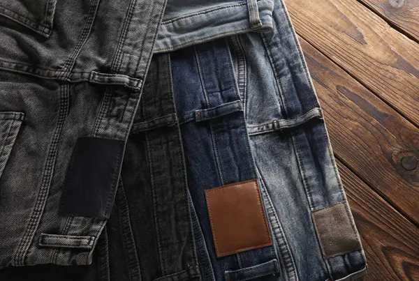 Ahşap arka planda bir sürü kot pantolon. Üst görünüm.
