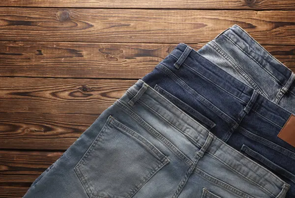 Ahşap arka planda bir sürü kot pantolon. Üst görünüm.