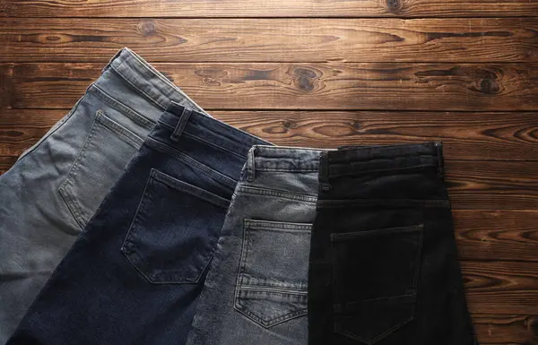 Ahşap arka planda bir sürü kot pantolon. Üst görünüm.