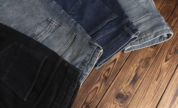 Ahşap arka planda bir sürü kot pantolon. Üst görünüm.