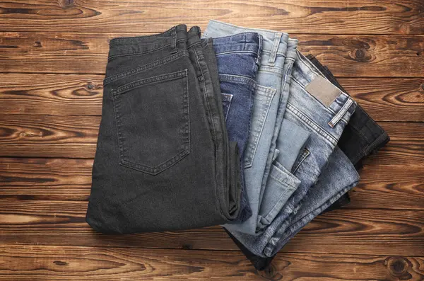 Ahşap arka planda bir sürü kot pantolon. Üst görünüm.