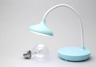 Masa LED lambası ve parlak ampul gri arkaplanda