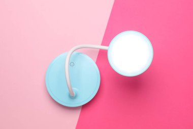 Pembe arka planda, masaüstü kablosuz esnek LED lamba. Üst görünüm