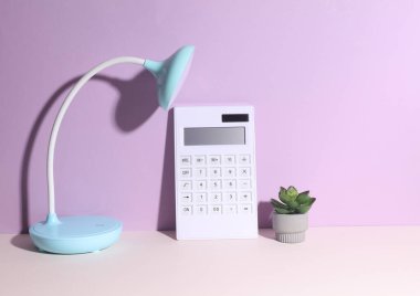 Hesap makineli LED masa lambası. Mor arka plan. Enerji tasarrufu, iş konsepti
