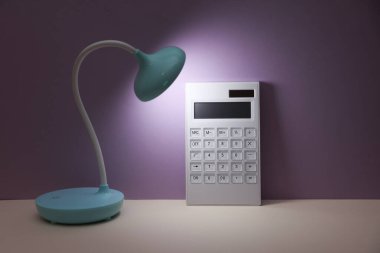 Hesap makineli LED masa lambası. Mor arka plan. Enerji tasarrufu, iş konsepti