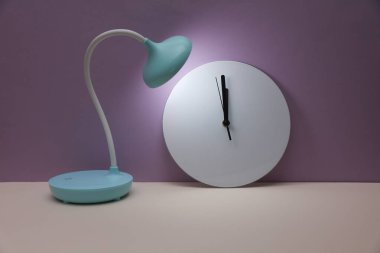 Mor arkaplanda saati olan masa lambası