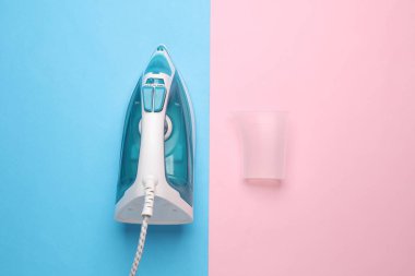 Mavi-pembe arka planda ütü yapmak için ütü. Üst görünüm