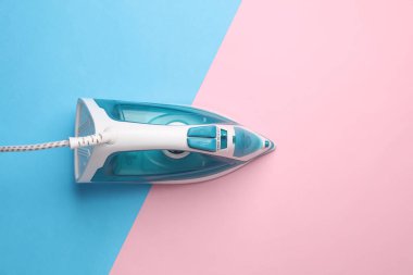 Mavi-pembe arka planda ütü yapmak için ütü. Üst görünüm