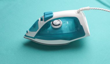 Mavi kumaş zemin üzerinde ütü yapılıyor