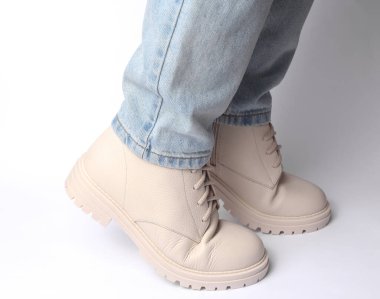 Kot pantolonlu kadın bacakları ve beyaz arka planda beyaz deri çizmeler. Moda konsepti