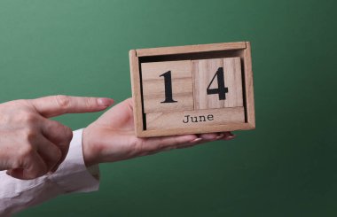14 Haziran tarihli ahşap blok takvimi yeşil arka planda.
