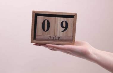 Kadın El, tahta blok takvimi tutuyor. Arkaplanda 9 Temmuz tarihi yazıyor.