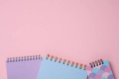 Pembe arka planda çeşitli not defterleri.