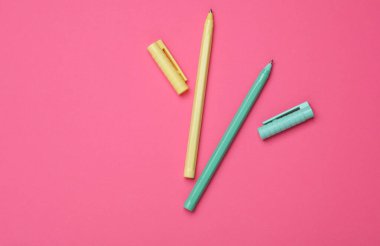 Pembe arka planda renkli kalemler