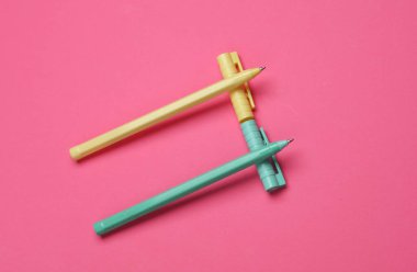 Pembe arka planda renkli kalemler