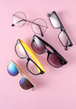 Pembe arka planda çeşitli güneş gözlüğü ve gözlükleri var.