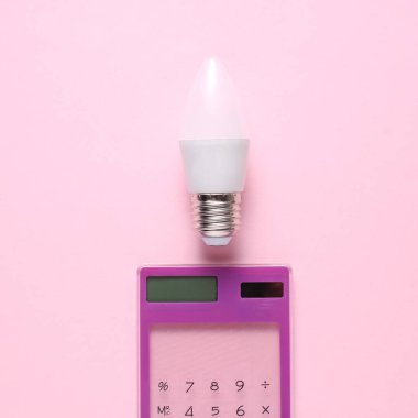 Pembe arka planda enerji tasarrufu sağlayan LED ampullü bir hesap makinesi. Yaratıcı fikir, iş kavramı