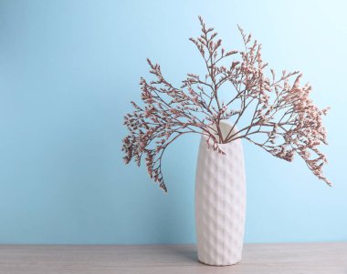 İskandinav tarzında minimalist vazo. Masada kurumuş çiçekler, mavi arka plan.