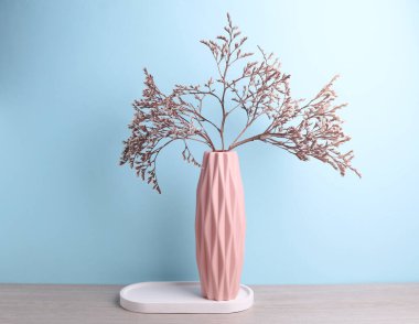 İskandinav tarzında minimalist bir vazo. Masada kurumuş çiçekler ve alçı tepsi var. Mavi arka plan.