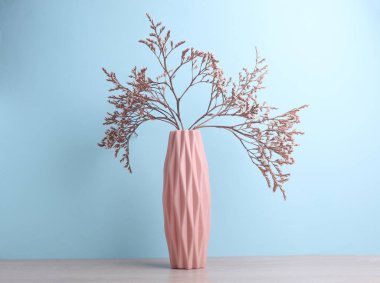 İskandinav tarzında minimalist vazo. Masada kurumuş çiçekler, mavi arka plan.