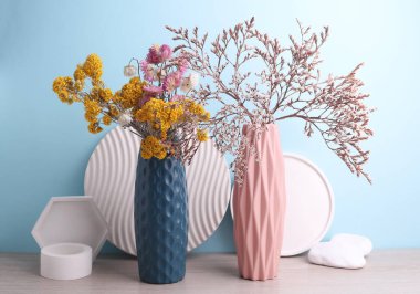 Mavi arka planda kuru çiçekli vazolar ve alçı şekillendiriciler. Minimalist natürmort