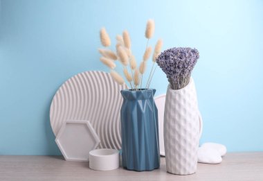 İçinde kuru lagurular, lavanta çiçekleri ve mavi arka planda alçı şekillendiriciler olan vazolar. Minimalist natürmort