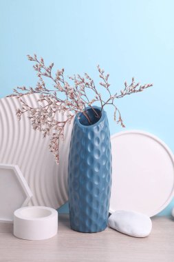 Mavi arkaplanda, alçı geometrik şekilli kuru çiçekli vazo.